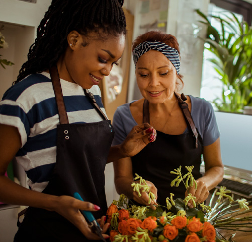 A young woman and an older woman working together on a flower arrangement